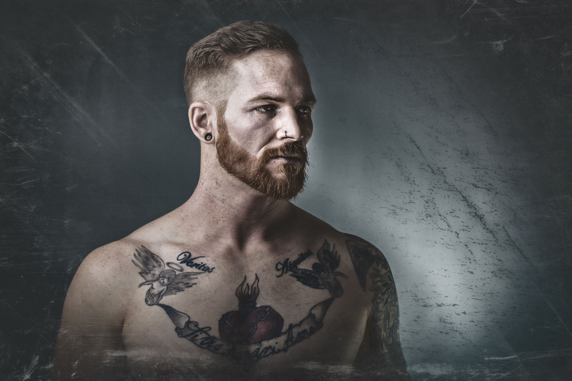 Portrait of a bearded, tattooed athlete against a textured grey wall — by Hamudi Leon