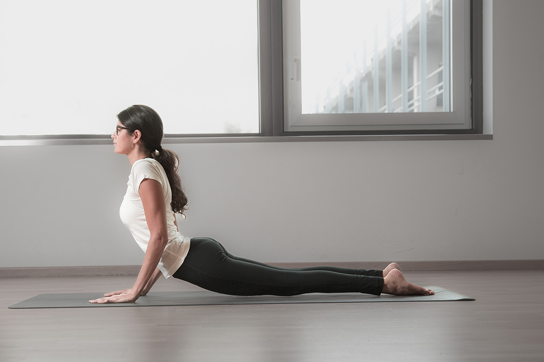 Woman in upward-facing dog on a mat in a bright, window-lit studio — sports photograph by Hamudi Leon