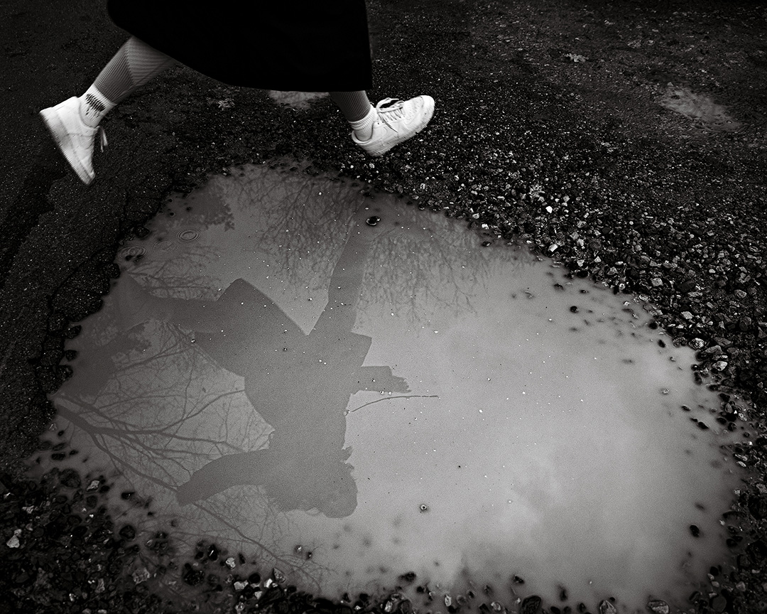 Street photography on a girl jumping around water black and white portrait